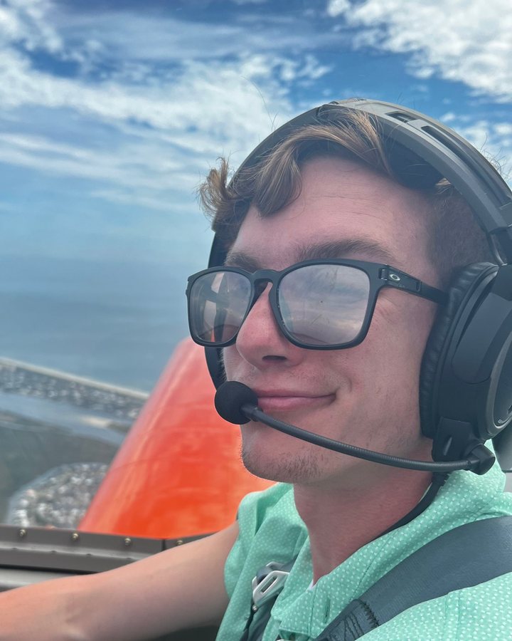 Brady Fredrickson in the cockpit, wearing a headset, with the Florida coast below