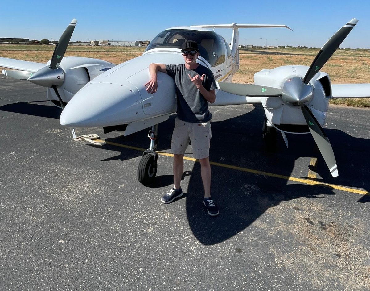 Brady Fredrickson on the ramp beside a twin-engine trainer under a clear blue sky